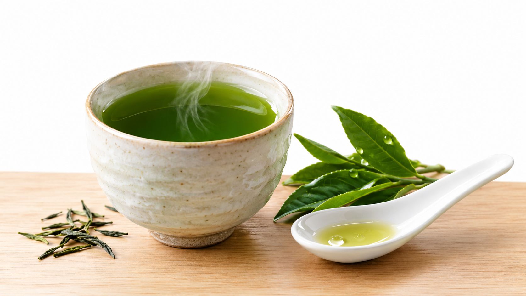 A steaming cup of vibrant green Gyokuro tea beside fresh tea leaves and a white tasting spoon.