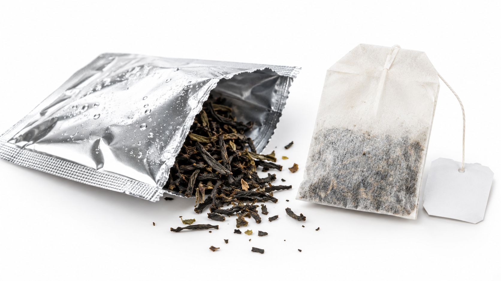 A silver foil pouch filled with dry loose tea leaves next to a classic paper tea bag.